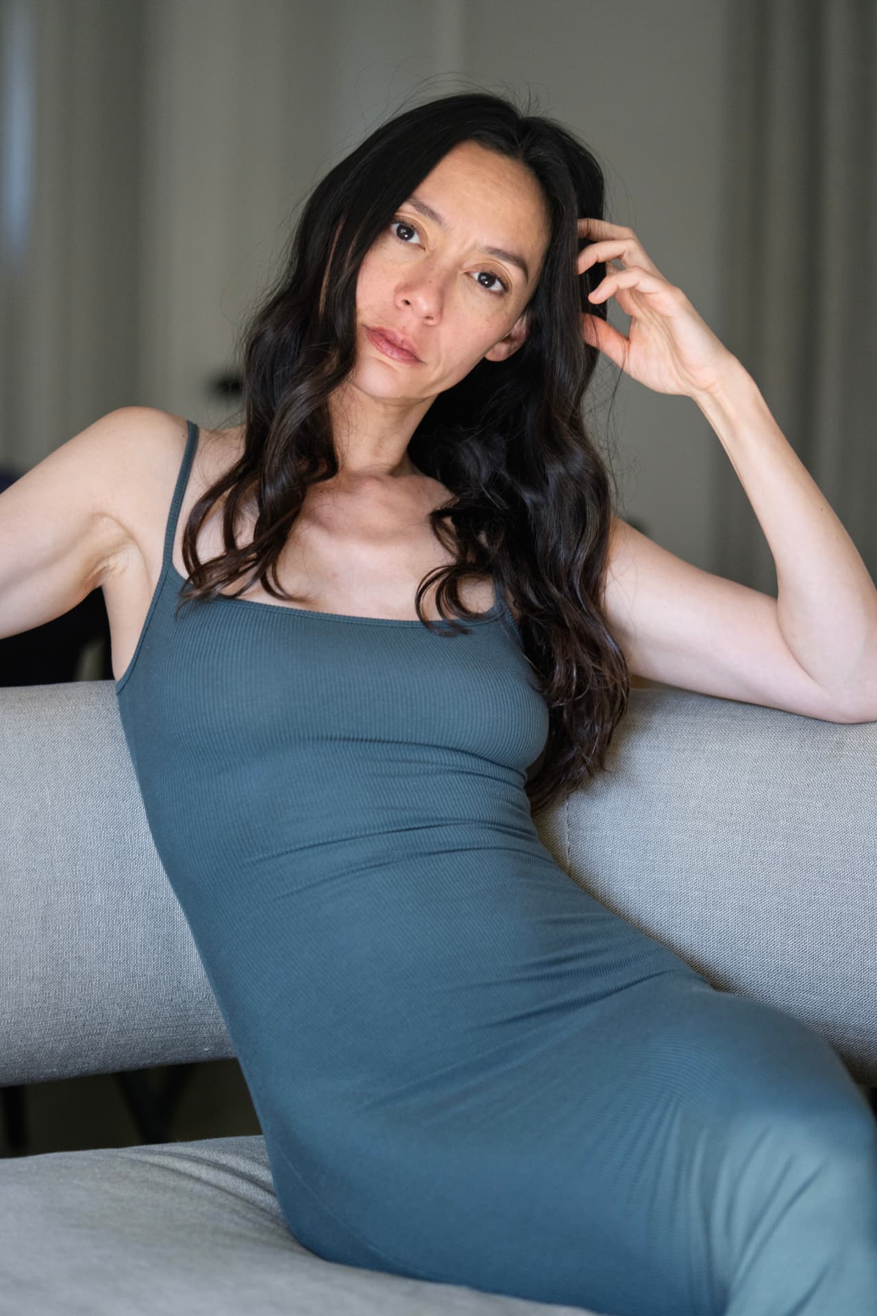 Lucia Micarelli seated on a sofa in a blue dress