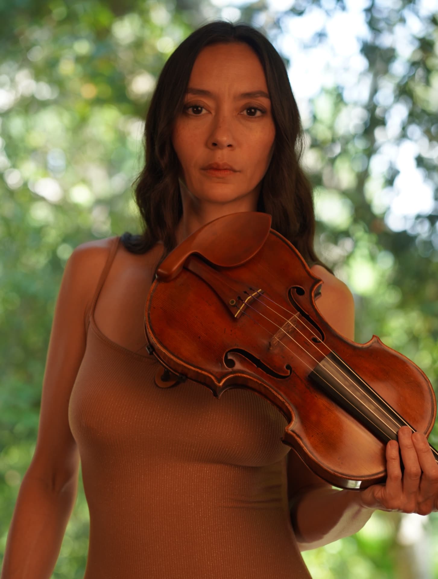 Lucia Micarelli holding her violin outdoors