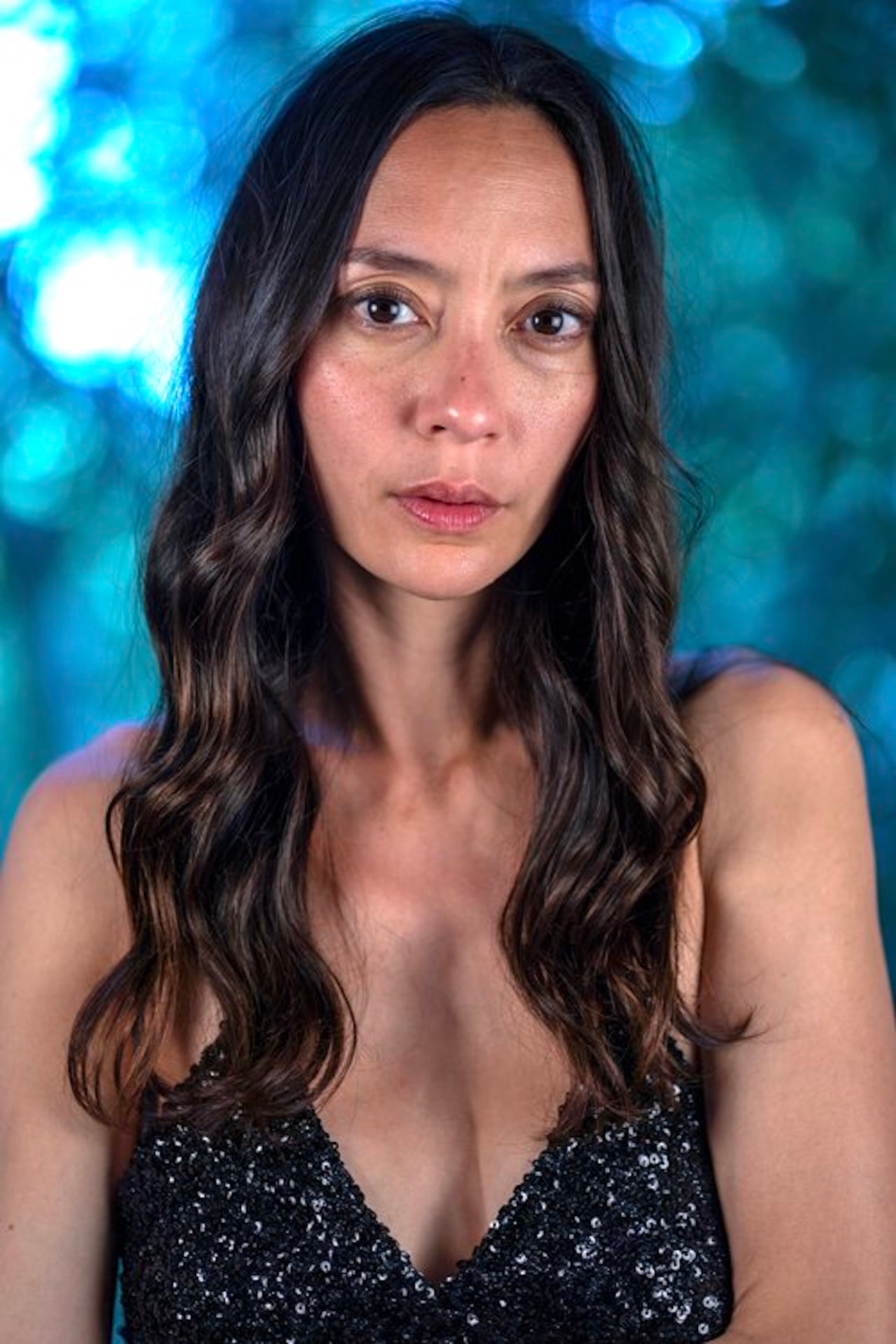 Lucia Micarelli in a black sequined dress against a blue background